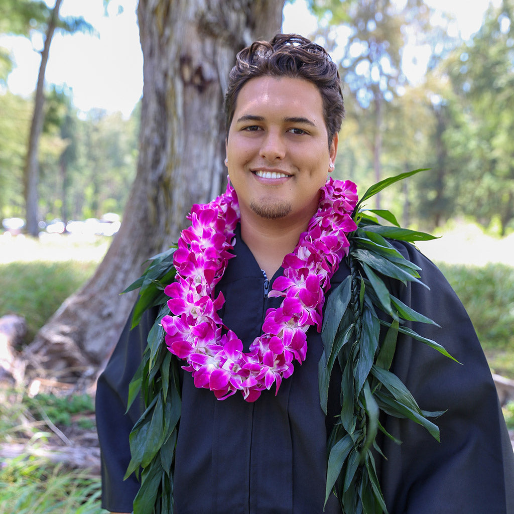 Man wearing maile ti leaf lei and double orchid lei for graduation