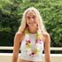Woman wearing a white tank top with floral necklace lei- orchid lei