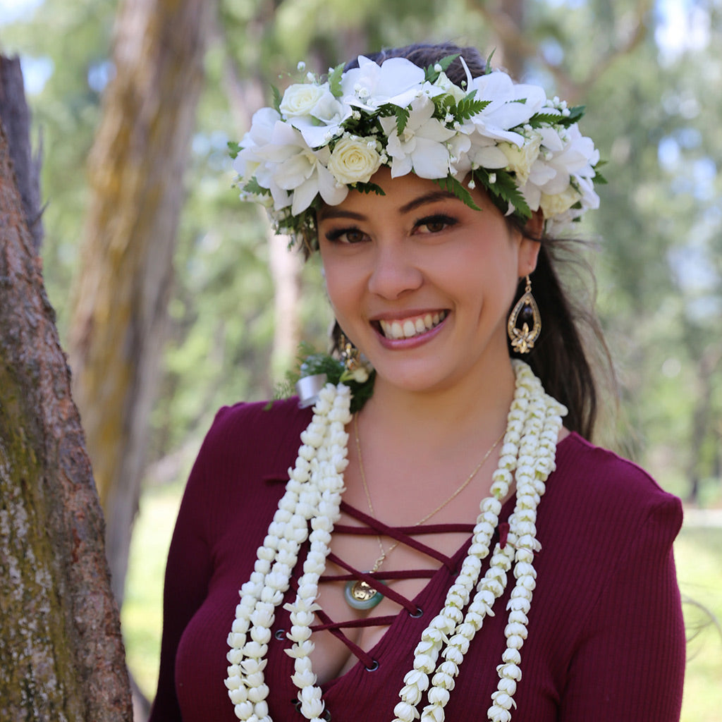 Woman wearing a handcrafted pikake three-strand lei and white orchid haku flower crown in Hawaii