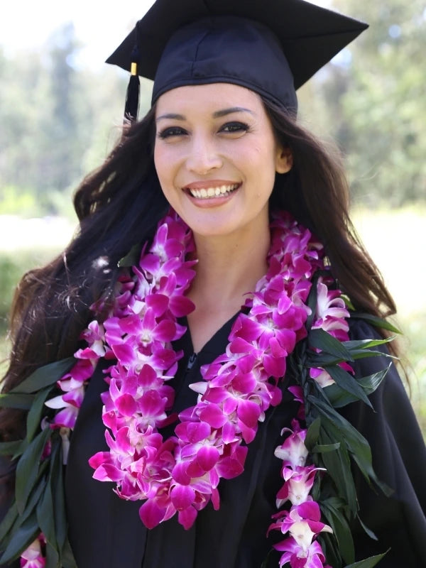 Graduate in cap and gown with double orchid lei & maile ti hawaiian lei for graduation 